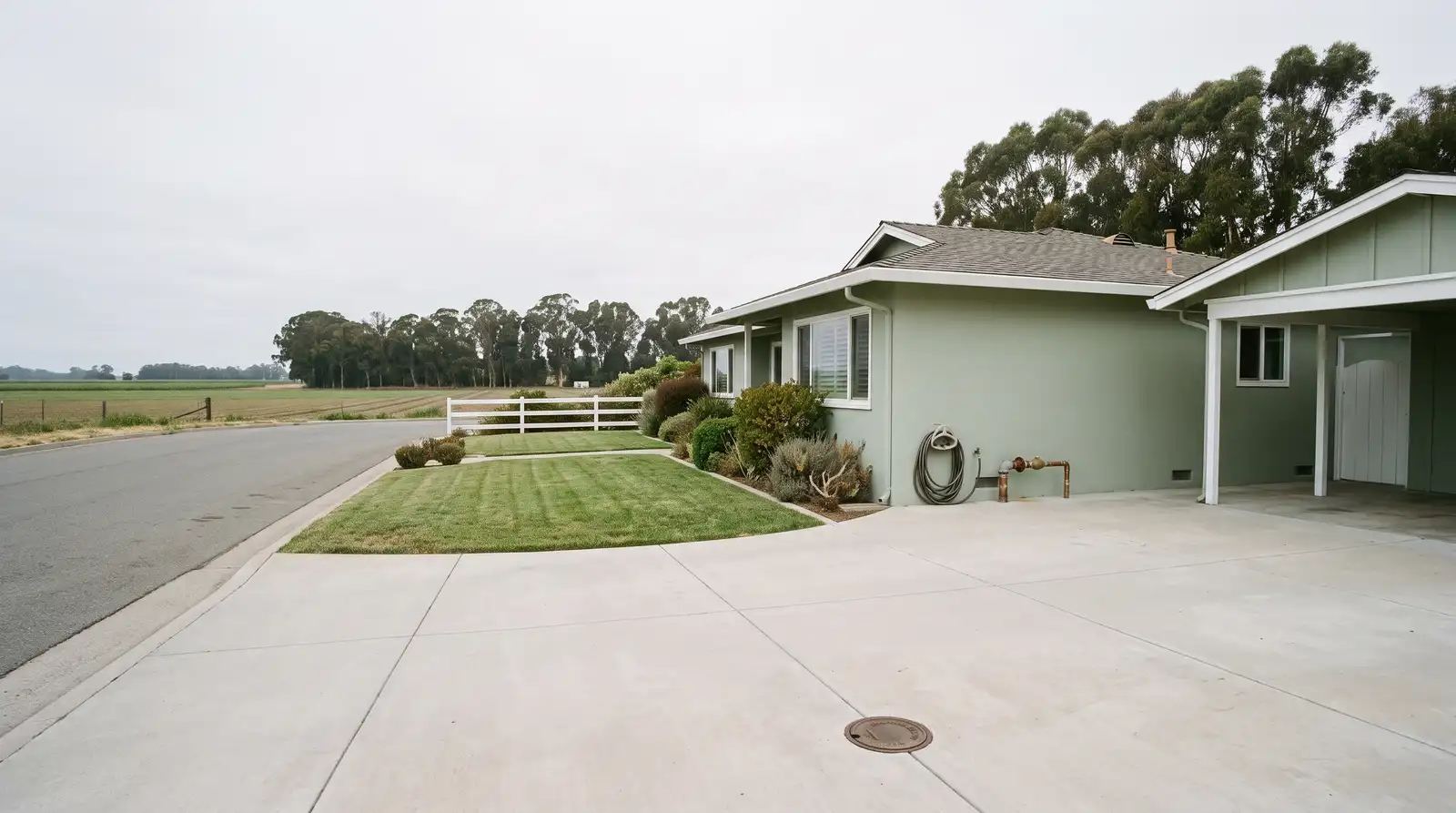 Single-story mid-century ranch house on a wide semi-rural Freedom street, with corroded galvanized supply pipe meeting newer copper at the wall